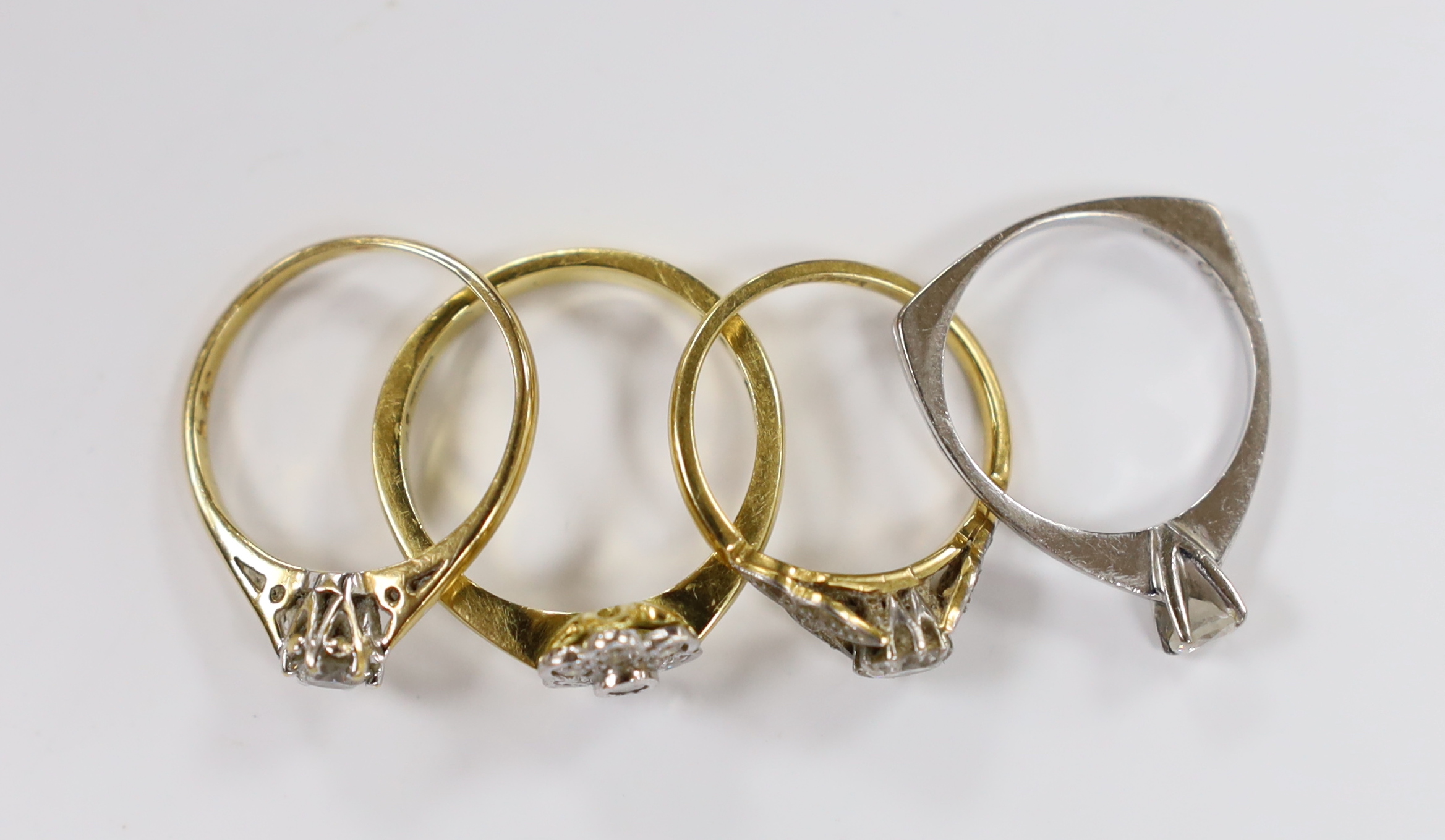 Three assorted 18ct and solitaire diamond rings and an 18ct gold and diamond set flower head ring, gross weight 10.8 grams.